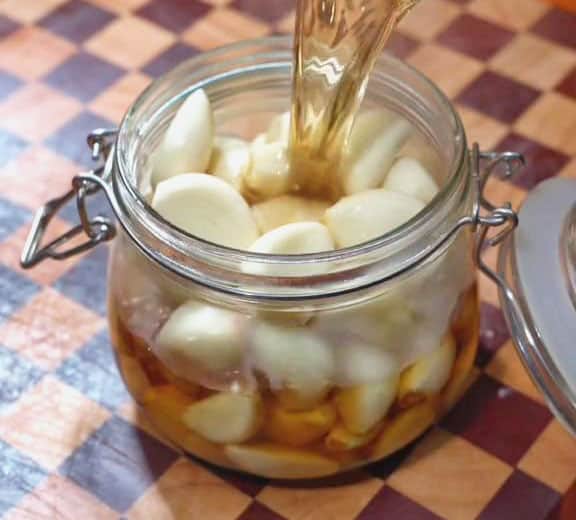 Pour the warm vinegar mixture over the garlic in the glass jar
